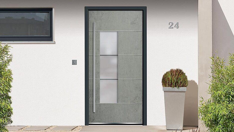 Haustür in Betonoptik Graue Haustür in Betonoptik mit schwarzem Rahmen vor weißer Wand