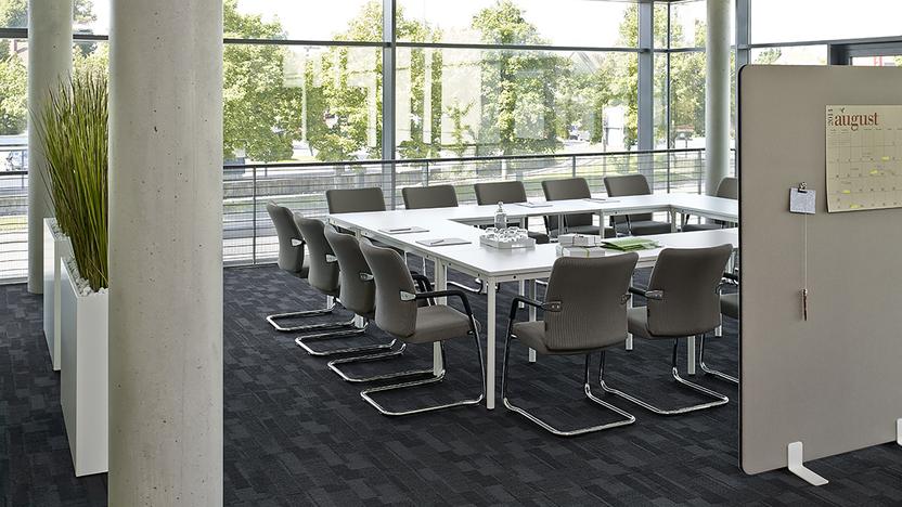 Konferenztisch im Büro Weißer Konferenztisch im Büro vor Trennwänden